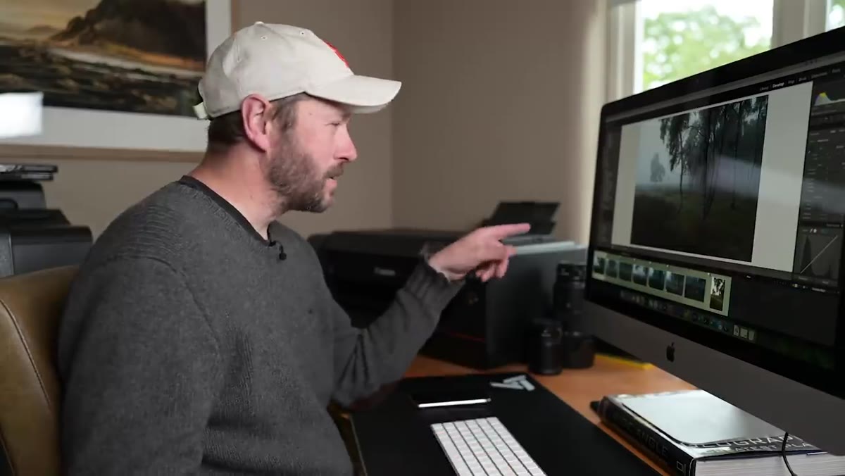 caption: Danson gesturing toward desktop printer on desk